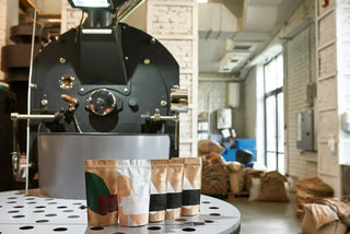Coffee bags on table in modern coffee roastery with industrial roasting machine